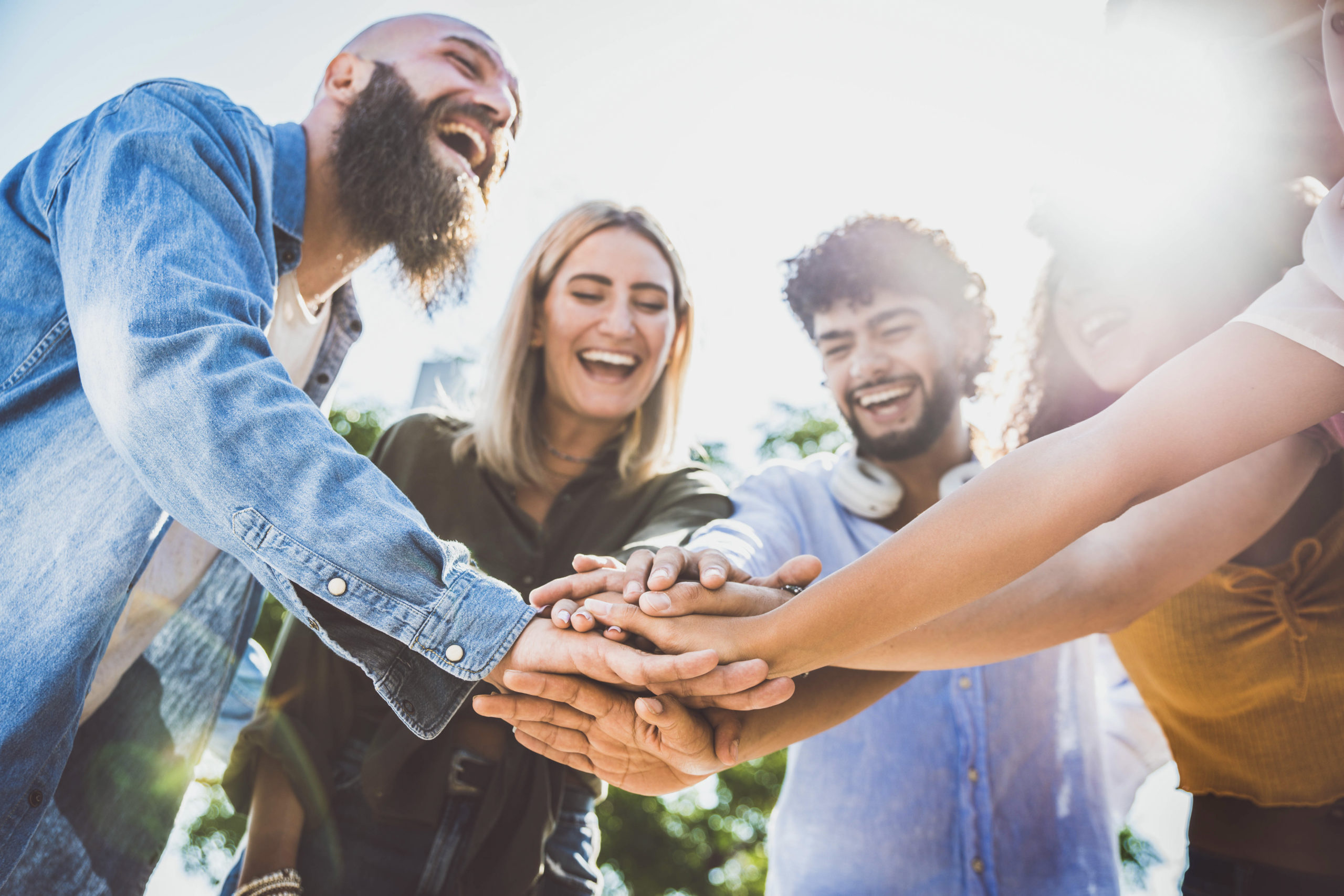 Multiracial happy young people stacking hands on top of each oth